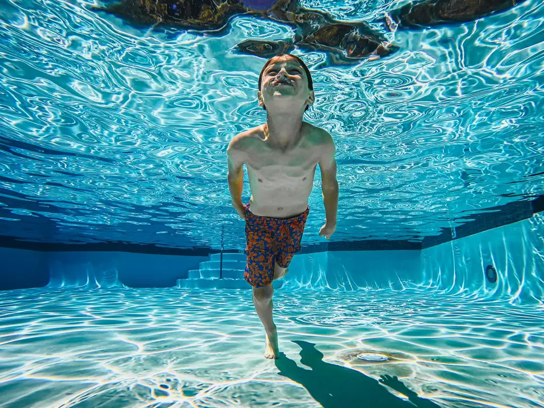 Kind zwemt onder water in een zonnig zwembad